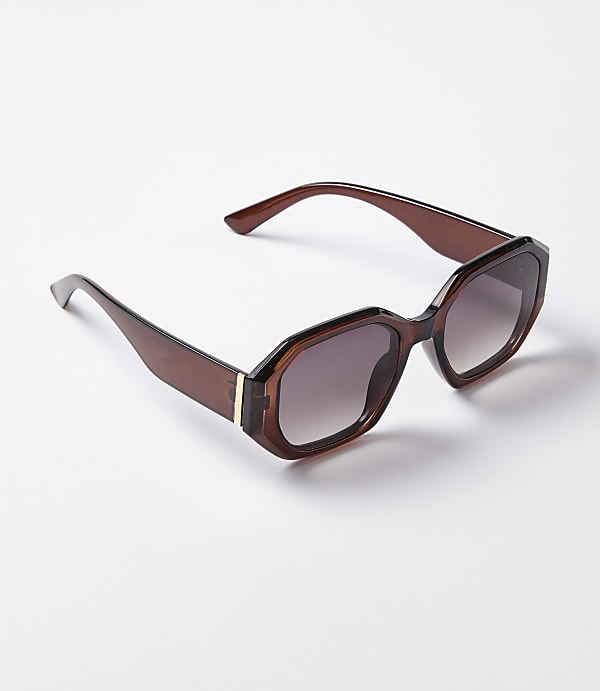 A pair of brown, hexagonal-shaped sunglasses with gradient lenses rests on a plain white background.