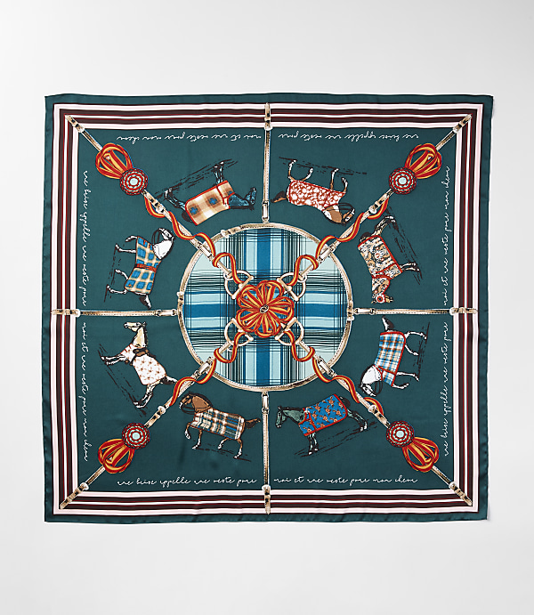 A square silk scarf with a dark teal background features a central circular design of plaid and ornate equestrian-themed elements, surrounded by a border of running horses in various patterned blankets and decorative tassels.