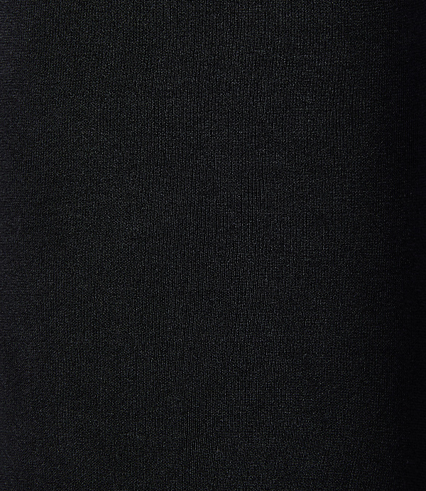 A black, textured fabric fills the frame, with subtle vertical ribbing visible in the foreground and a gradient of darkness towards the right background.
