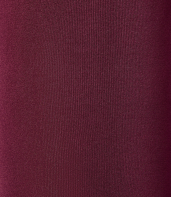 A close-up of a textured, deep red fabric fills the frame, with subtle vertical ribbing creating a sense of depth.