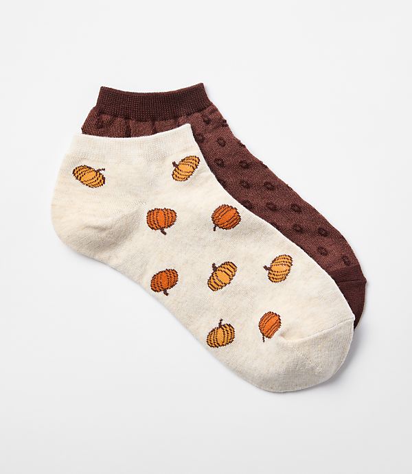 A pair of cream-colored ankle socks with pumpkin patterns and a dark red sock with a textured pattern rest on a white background.