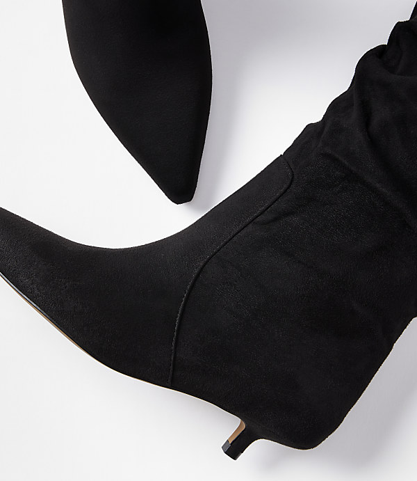 A close-up of two black suede kitten-heel boots with pointed toes is presented against a plain white background.