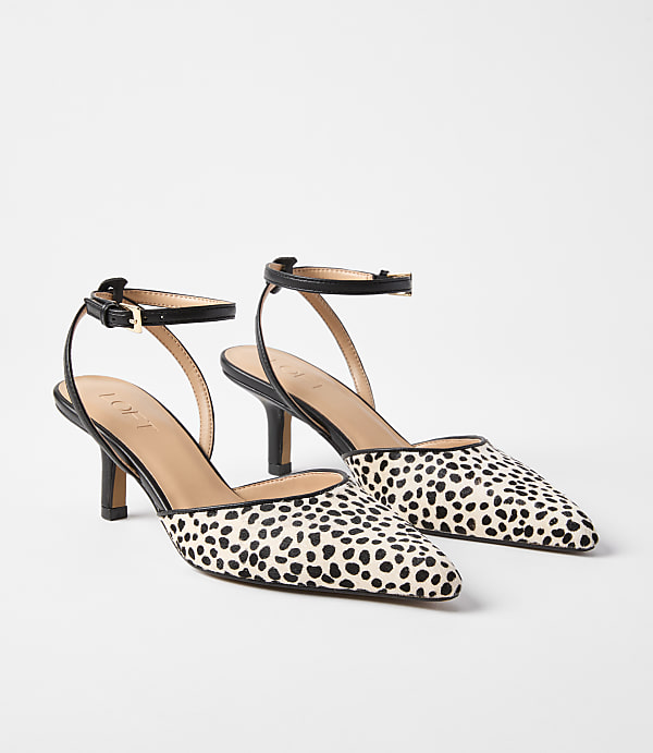 A pair of dalmatian-print kitten heels with ankle straps rests on a plain white background.