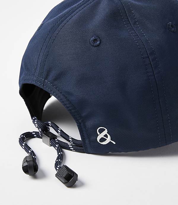 A close-up of a navy blue baseball cap with an adjustable drawstring in the foreground is set against a plain white background.