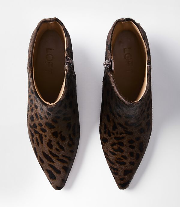 A pair of leopard-print ankle boots with pointed toes are laid out on a white background.