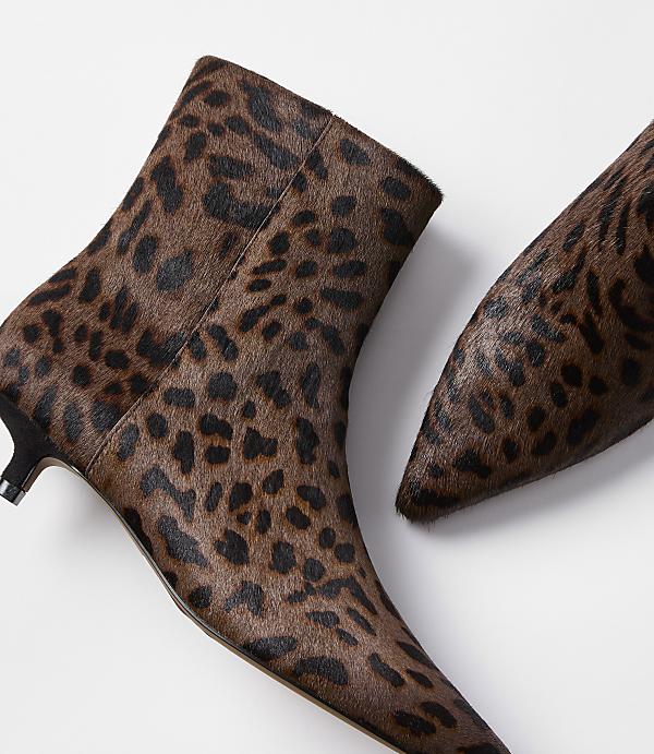 A pair of leopard-print calf-hair ankle boots with pointed toes and kitten heels rests on a plain white background.