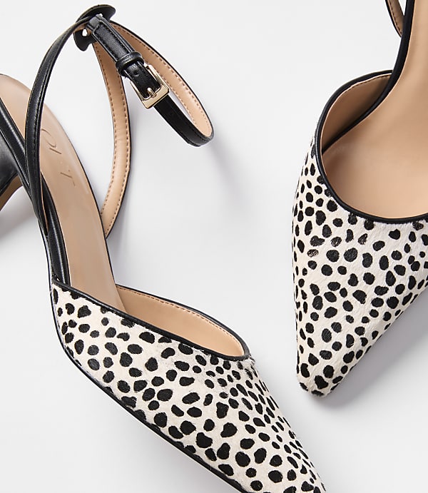 A pair of dalmatian-print slingback heels with black straps are displayed against a plain white background.