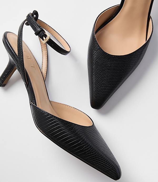 A pair of black textured slingback heels with ankle straps are displayed against a plain white background.