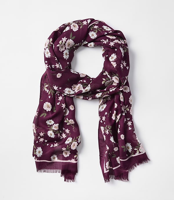 A burgundy floral scarf with frayed edges is laid out against a plain white background.