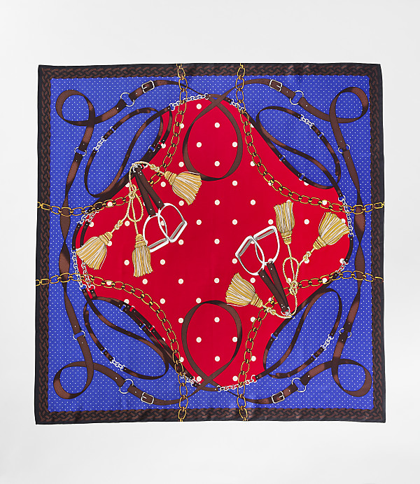 A red and white polka dot center is surrounded by a blue border with equestrian-themed motifs of stirrups, tassels, and belts.