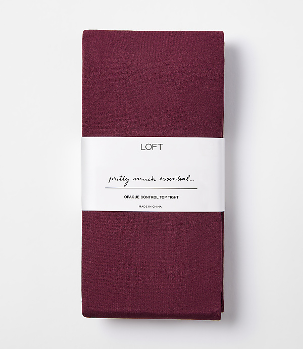 A folded pair of burgundy opaque control top tights with a white band displaying the brand "LOFT" and product details is presented against a plain white background.