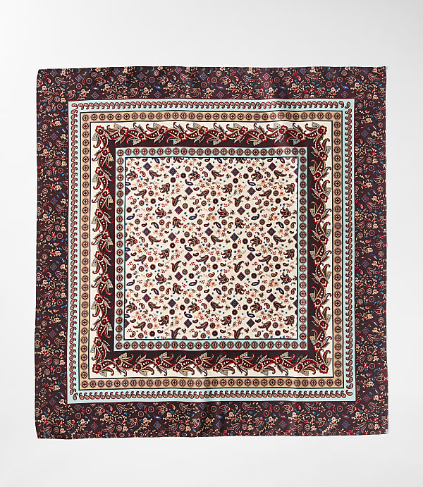 A square silk scarf with intricate paisley and floral patterns in shades of burgundy and cream is laid flat against a white background.