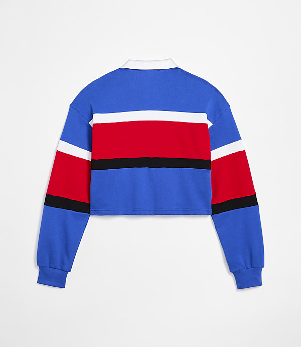 A cropped, long-sleeved rugby shirt with blue, white, and red stripes is displayed against a plain white background.