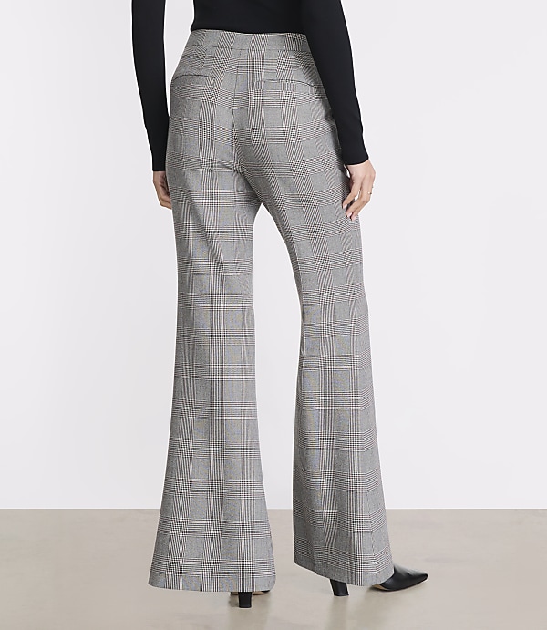 A person wearing plaid bell-bottom pants stands against a plain white background.