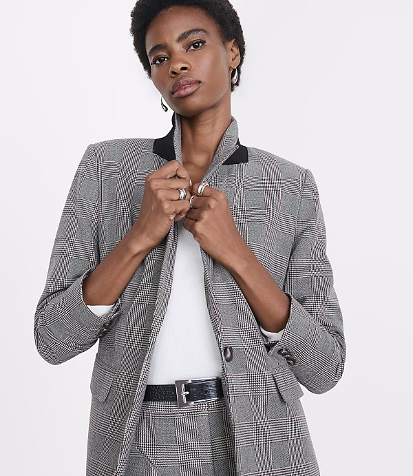 A woman in a plaid blazer and pants stands against a plain white background.