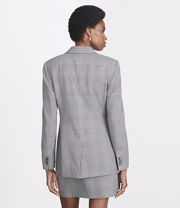 A woman in a plaid blazer and skirt stands against a plain white background.