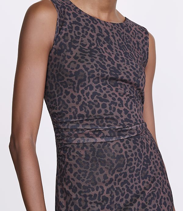 A person in a leopard-print top stands against a plain white background.