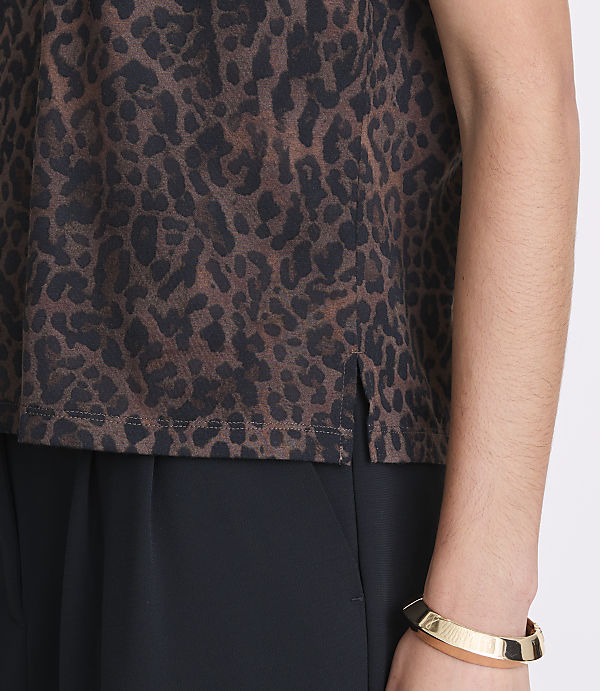 A close-up shot features a person's torso wearing a brown leopard-print top with a slit hem and black pants, accessorized with a gold bracelet on their arm.