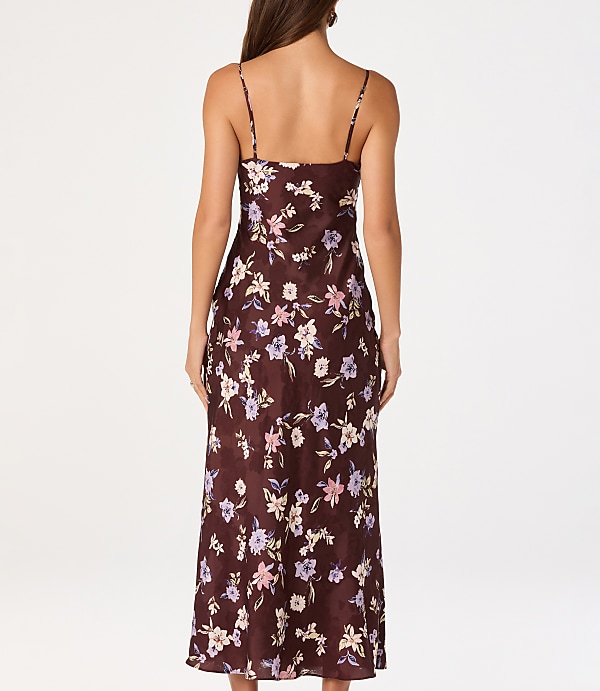 A woman in a floral slip dress stands against a plain white background.