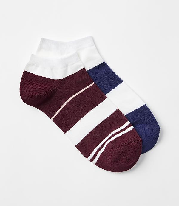 Two ankle socks, one white with a football emblem and the other beige with a bow, are arranged against a plain white background.