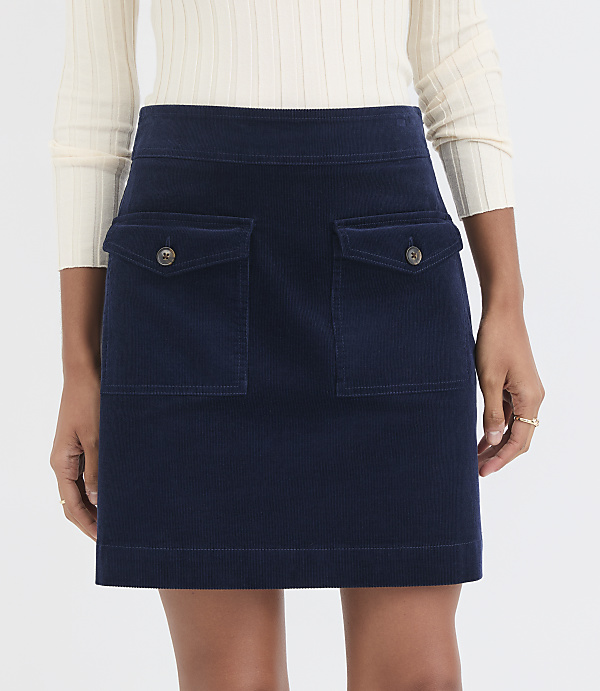 A navy blue corduroy skirt with two front pockets is worn by a person against a plain white background.