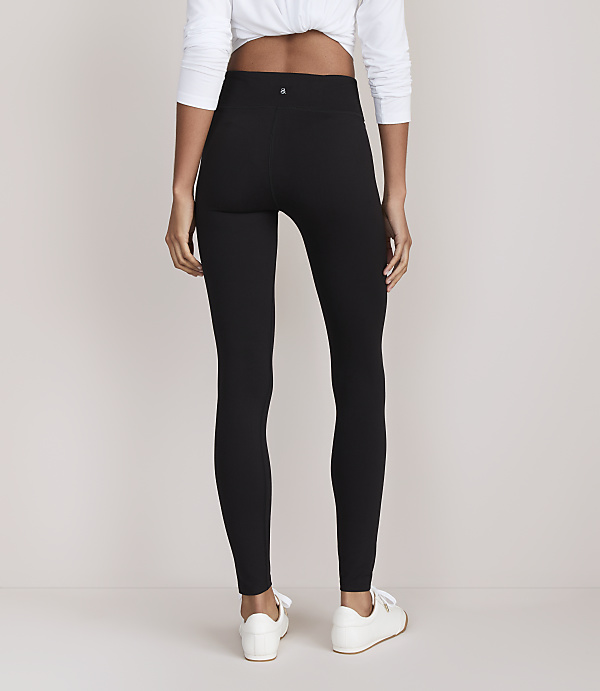 A person wearing black leggings and white sneakers stands against a plain white background.