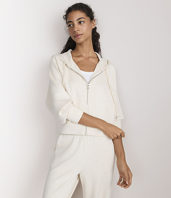 A woman in a cream-colored loungewear set stands against a plain white background.