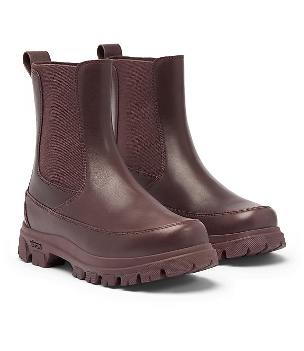 A pair of burgundy leather Chelsea boots with thick lug soles stand on a white background.