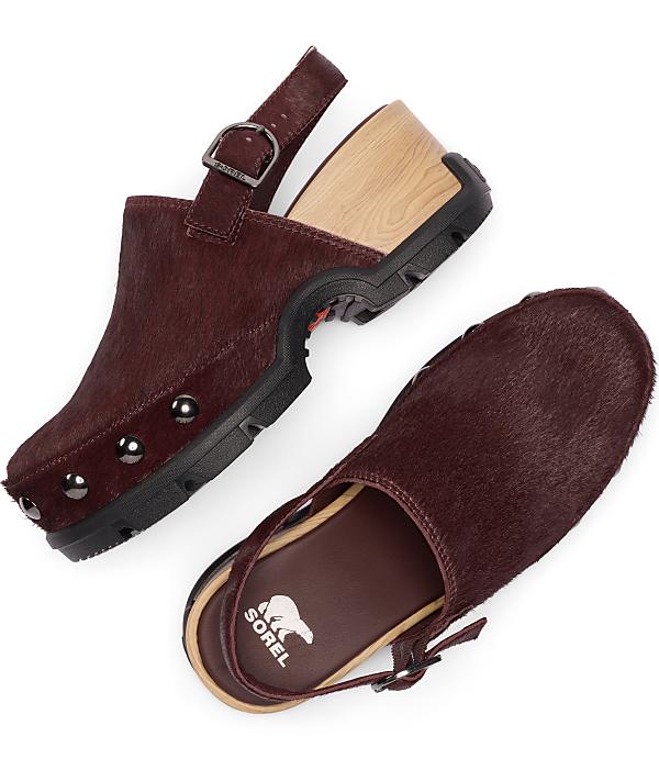 A pair of burgundy, furry clogs with wooden heels and metal studs are displayed against a plain white background.