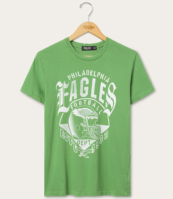 A green t-shirt with a Philadelphia Eagles football graphic hangs on a wooden hanger against a plain, light-colored background.