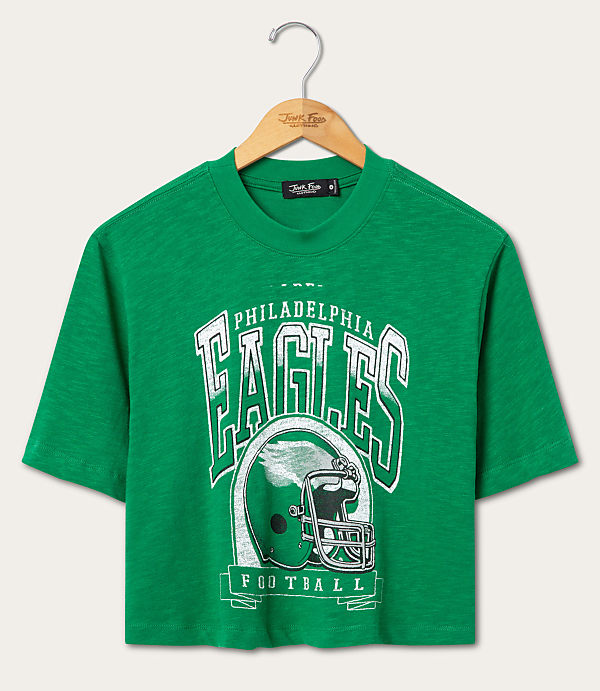 A green Philadelphia Eagles football t-shirt hangs on a wooden hanger against a plain white background.