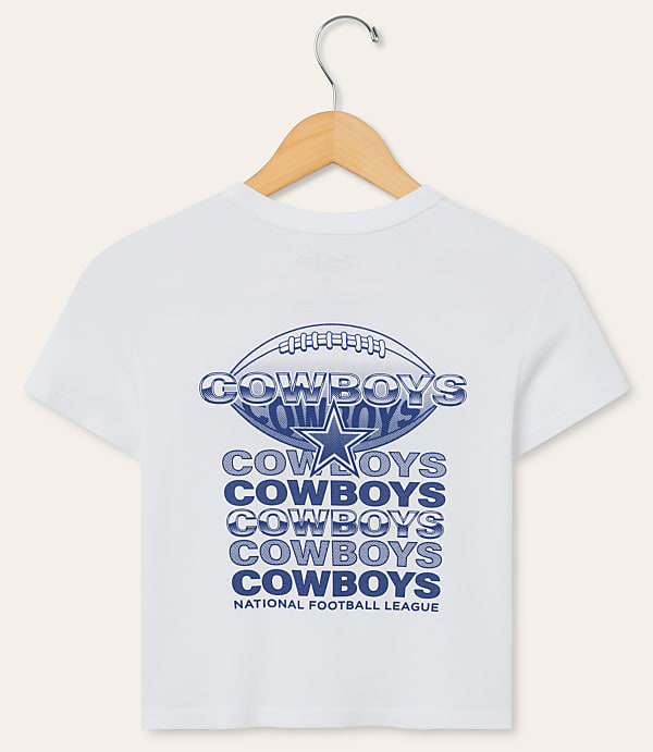 A white t-shirt with a Dallas Cowboys logo and repeated "Cowboys" text is displayed on a hanger against a plain white background.