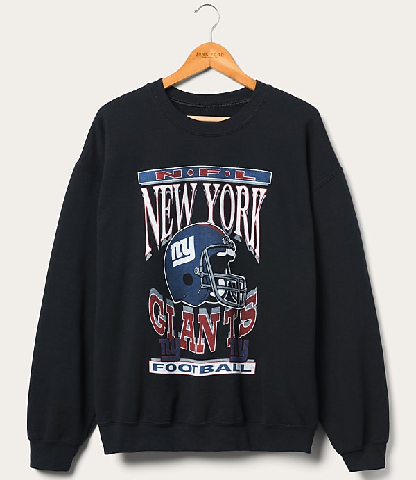 A dark blue New York Giants sweatshirt with a graphic of a helmet and team name is displayed on a wooden hanger against a plain, light-colored background.