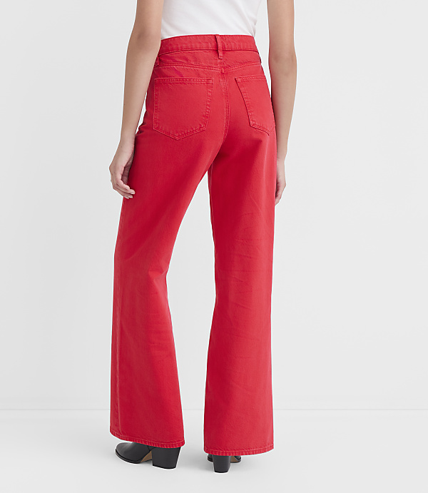 A person wearing bright red wide-leg jeans stands against a plain white background.