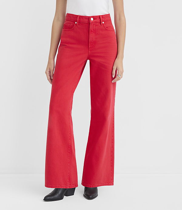 A person wearing bright red flared jeans and black boots stands against a plain white background.