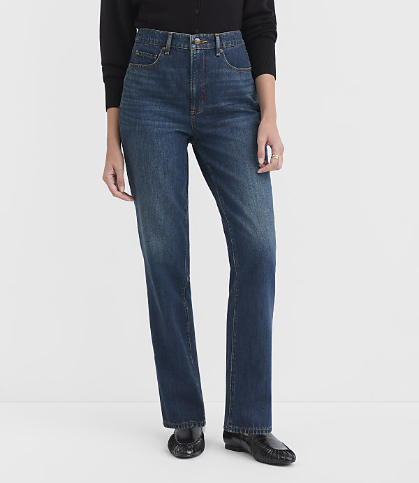 A person wearing dark blue high-waisted jeans and black loafers stands against a plain white background.