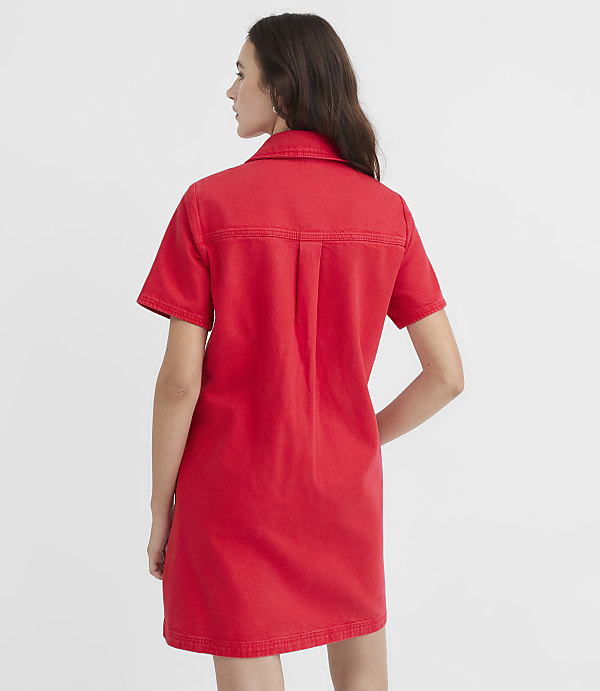 A woman in a red denim dress stands against a plain white background.