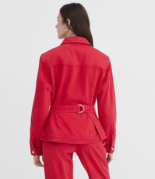 A woman in a red denim jacket and pants stands against a plain white background.