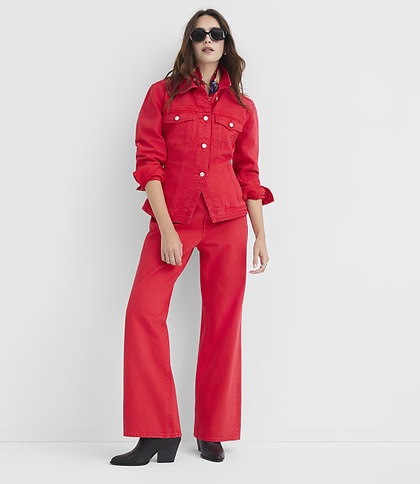 A woman in a red denim jacket and pants stands against a plain white background.