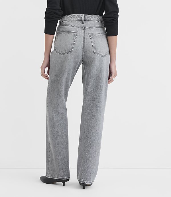 A person wearing grey wide-leg jeans and black shoes stands against a plain white background.