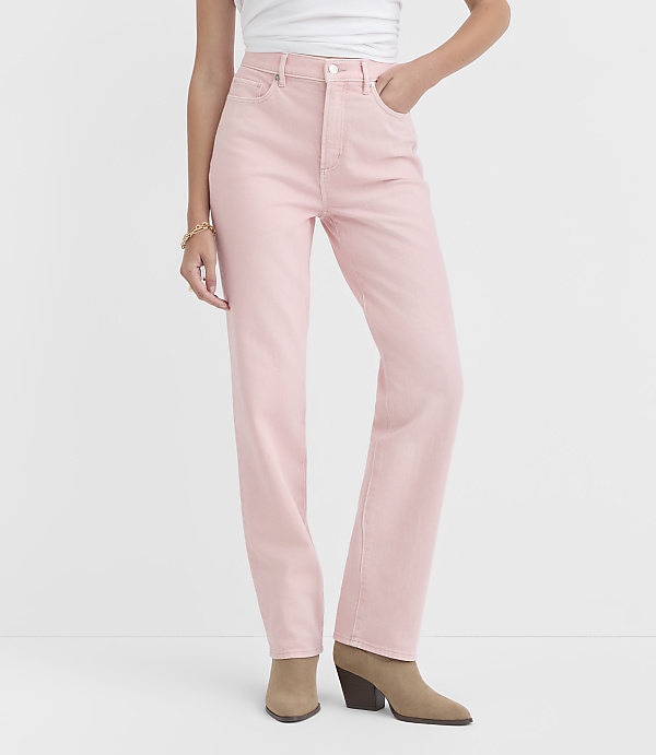 A person wearing light pink denim jeans and tan ankle boots stands against a plain white background.