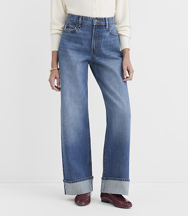 A person stands in cuffed wide-leg jeans and burgundy loafers against a plain white background.
