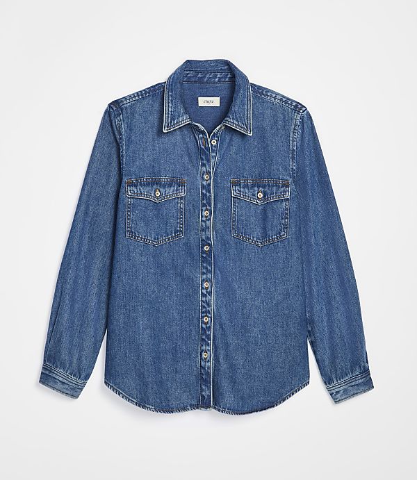 A blue denim shirt with two chest pockets lies flat against a plain white background.