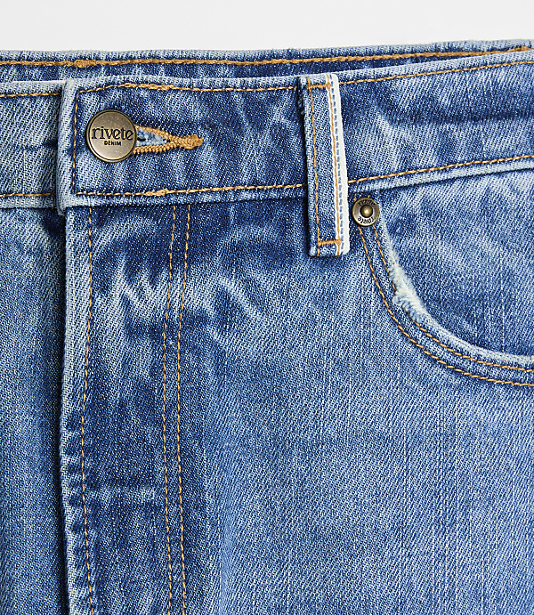 A close-up of blue denim jeans with a metal button and pocket in the foreground, set against a plain white background.