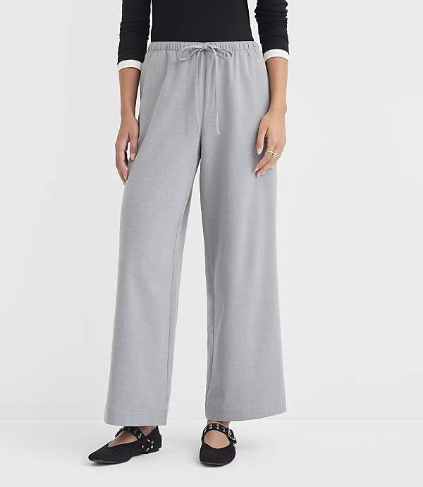 A person stands in light gray wide-leg pants and black flats against a plain white background.