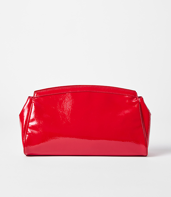 A shiny red clutch rests on a white surface against a plain white background.