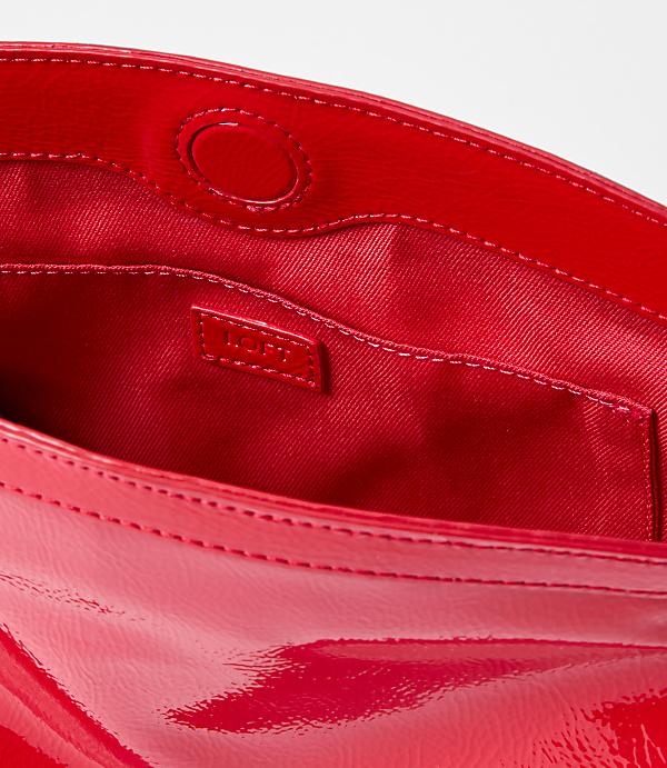 A bright red patent leather clutch with a satin lining and a small interior pocket is presented against a plain white background.