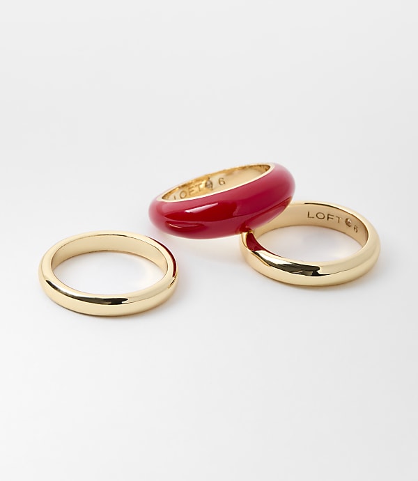 Three gold rings and one red resin ring are arranged on a white background.