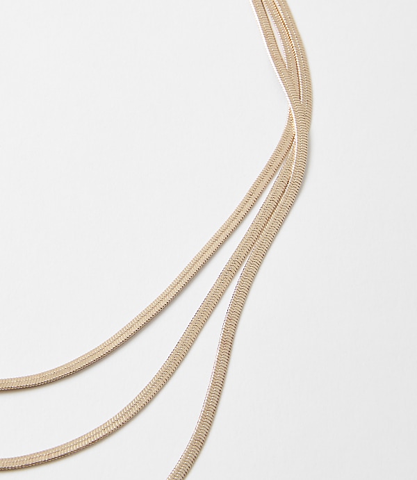 Three delicate rose gold chains curve across a plain white background.