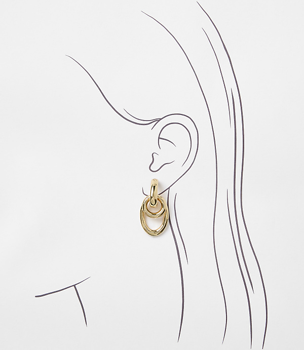 A gold-toned interlocking oval earring hangs from a stylized ear against a white background.